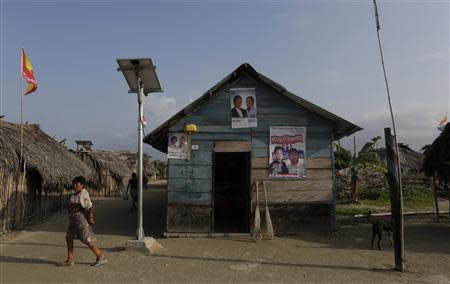 A Guna woman walk past a house with a solar panel in Caledonia island in the region of Guna Yala April 4, 2014. REUTERS/ Carlos Jasso