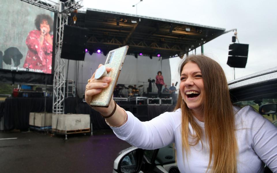 A girl in a car takes a selfie as Casey Donovan performs on stage during a media call to showcase how a drive-in live entertainment venue will operate ahead of its opening in July in the suburb of Tempe - GETTY IMAGES