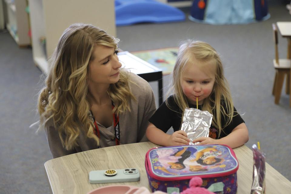 Second grade teacher Ashlie Monroe stops in at Endeavor Elementary's onsite daycare during her lunch hour to see her daughter Carlie, 3, on Feb. 29, 2024, in Nampa, Idaho. (Carly Flandro/Idaho Education News via AP)