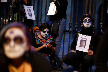 Activists with their faces painted to look like the popular Mexican figure "Catrina" hold pictures as they take part in a march against femicide during the Day of the Dead in Mexico City, Mexico November 1, 2017. The word on the sign reads "Justice" . REUTERS/Carlos Jasso