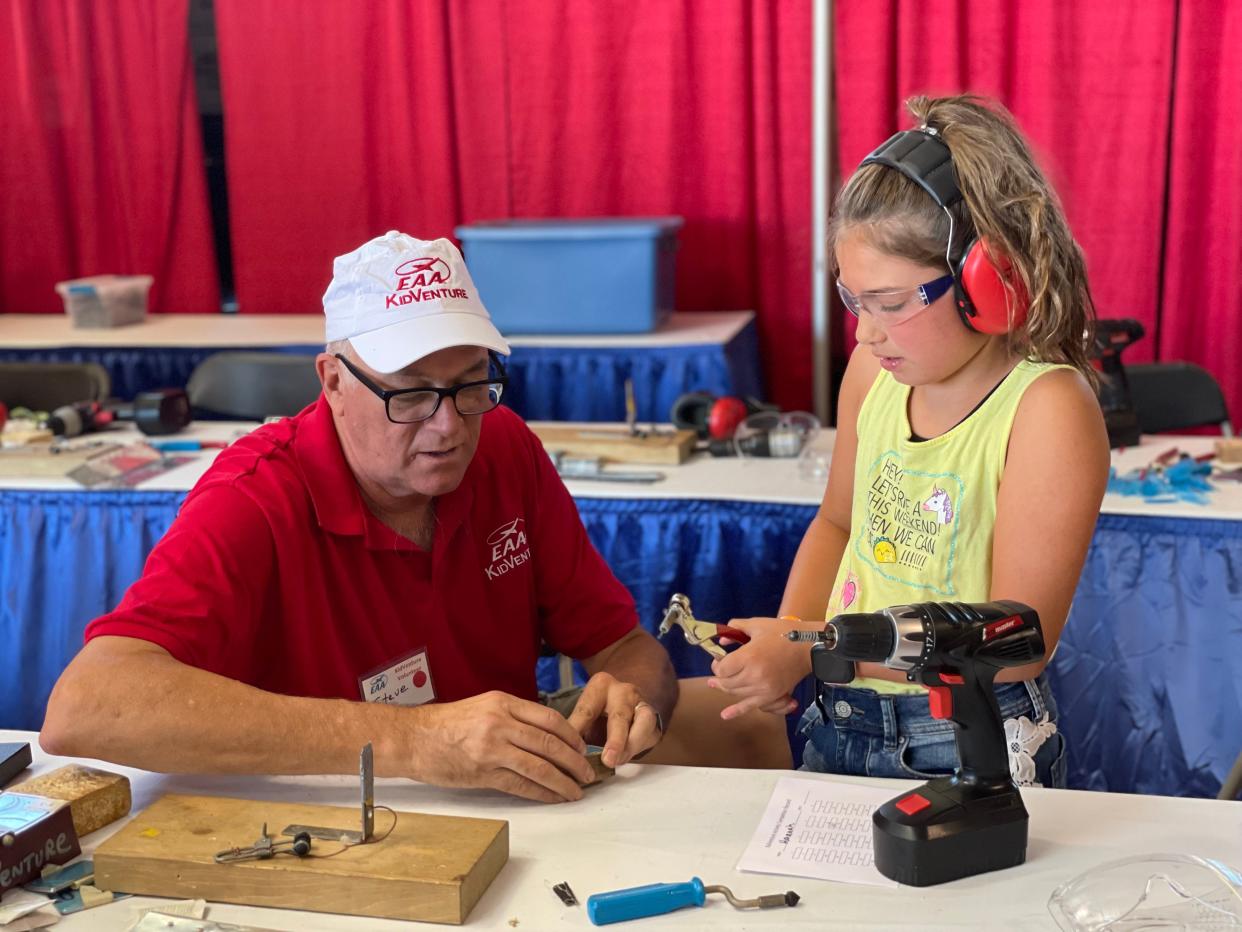 Steve McCutchan helps Hannah Maffet make a custom wing rivet pin at KidVenture at EAA AirVenture on July 25, 2022.