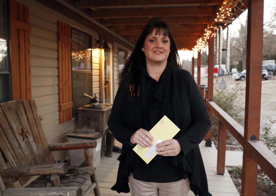 In this Thursday, Dec. 20, 2018 photo, Reagen Adair holds on to a RIP Medical Debt yellow envelope as she poses for a photo at her home in Murchison, Texas. The co-founders of RIP Medical Debt buy millions of dollars in past-due medical debt for pennies on the dollar. But instead of hounding people to pay, they send letters saying the debt is erased, no strings attached. (AP Photo/Tony Gutierrez)