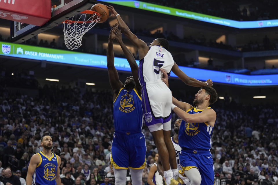 Sacramento Kings guard De'Aaron Fox (5) dunks over Golden State Warriors forward Draymond Green (23) during the first half of an NBA basketball play-in tournament game Tuesday, April 16, 2024, in Sacramento, Calif. (AP Photo/Godofredo A. Vásquez)