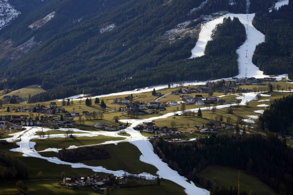 FILE - People ski on a strip of snow near Schladming, Austria, Friday, Jan. 6, 2023. Mother Nature and global warming are having just as much say about when and where to hold ski races these days as the International Ski Federation. Warm weather and a lack of snow wiped out nearly a month of racing at the start of this season. (AP Photo/Matthias Schrader, File)