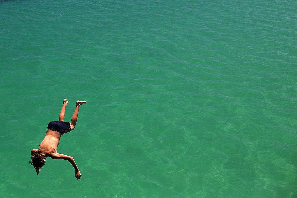 A teenager jumps from the jetty during a heat wave at Glenelg beach on 13 January, 2014 in Adelaide, Australia: Getty