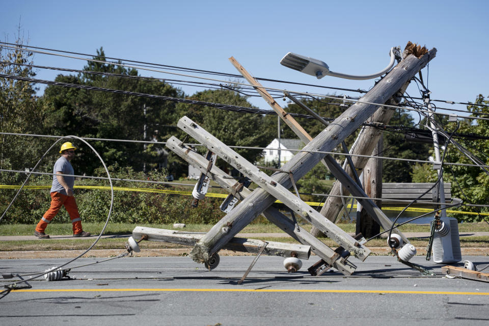 A worker walks past a downed power pole caused by post-tropical storm Fiona in Dartmouth, Nova Scotia, Sunday, Sept. 25, 2022. Hundreds of thousands of people in Atlantic Canada remain without power and officials are trying to assess the scope of devastation from former Hurricane Fiona. It swept away houses, stripped off roofs and blocked roads across the country’s Atlantic provinces. (Darren Calabrese/The Canadian Press via AP)