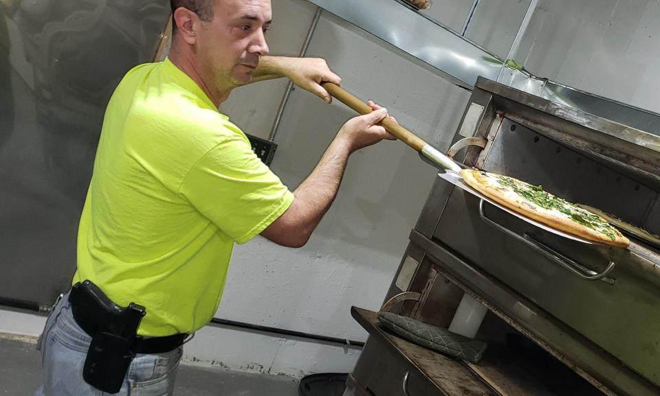 Saluda Whistle Stop Pizza & Wings co-owner Jason Smith puts a pizza in the oven.