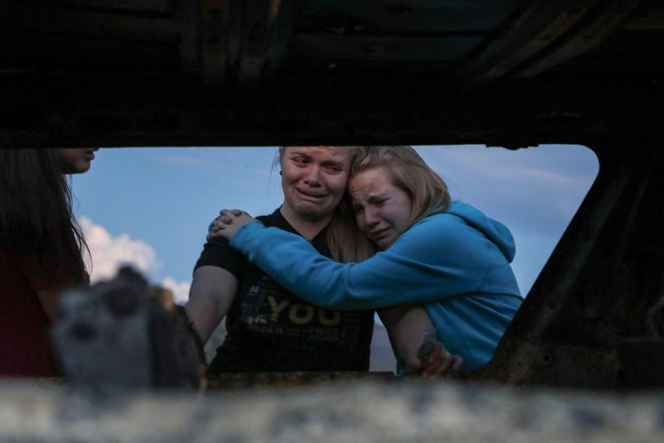 Members of the Lebaron family mourn while they watch the burned car where part of the nine murdered members of the family were killed and burned during an gunmen ambush on Bavispe, Sonora mountains, Mexico.