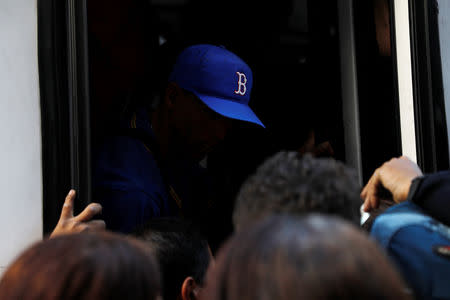 A man wearing a baseball hat is seen inside a bus as people try to board, during a blackout in Caracas, Venezuela March 7, 2019. REUTERS/ Carlos Jasso