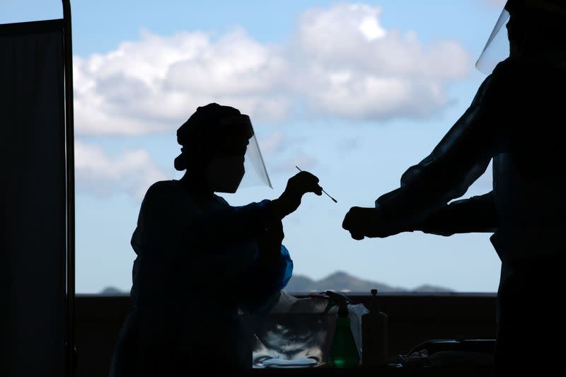 A health worker puts a swab sample from a taxi driver into a container for COVID-19 test at a makeshift testing station in a parking lot following the coronavirus disease (COVID-19) outbreak in Hong Kong