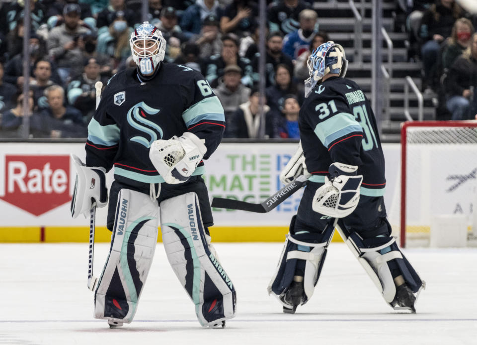 Seattle Kraken goalkeeper Chris Driedger, left, leaves the ice after getting replaced by Philipp Grubauer during the second period of an NHL hockey game against the Colorado Avalanche, Friday, Nov. 19, 2021, in Seattle. (AP Photo/Stephen Brashear)