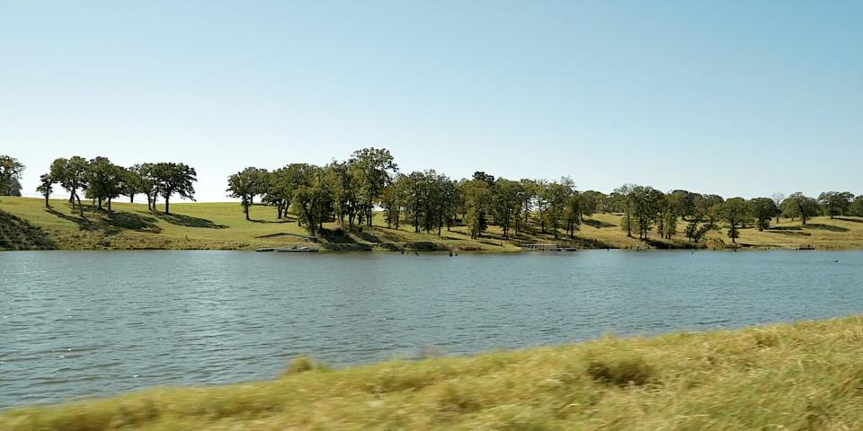 A wide, ground-level view of a lake, with trees along the shoreline.