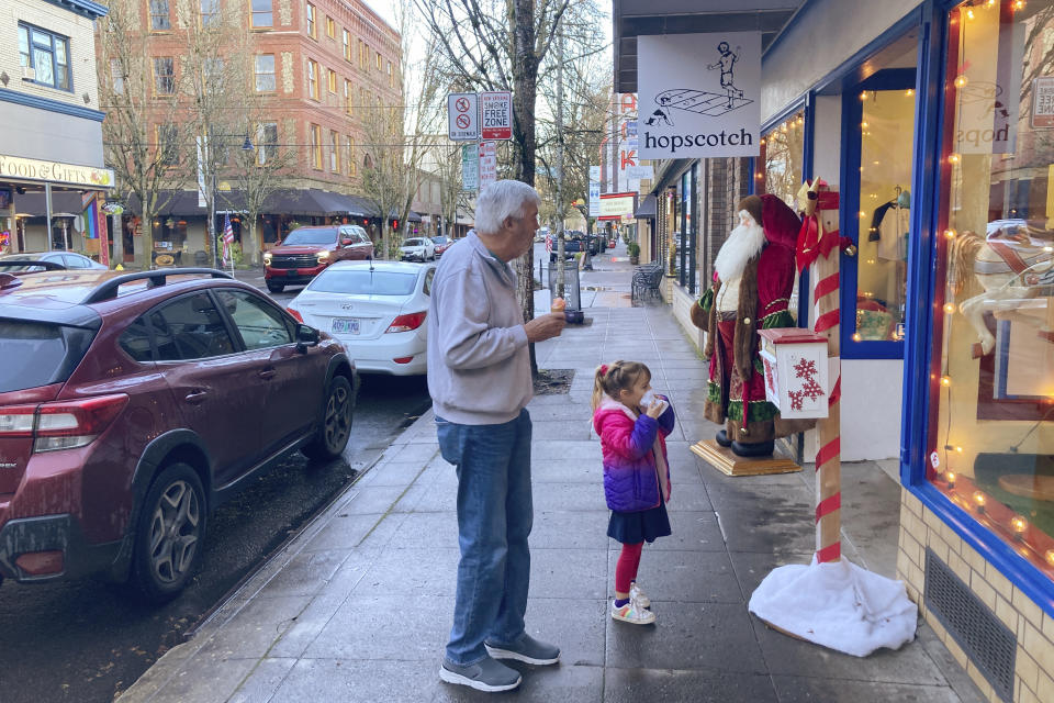 A man and a girl eat ice cream cones while window shopping in the picturesque town of McMinnville, Ore., on Thursday, Dec. 9, 2021. Like many other towns in the U.S., McMinnville was hit by the opioid epidemic, leaving overdoses, addiction, homelessness and wrecked families in its wake. States, counties and cities are on the precipice of receiving billions of dollars in the second-biggest legal settlement in U.S. history. (AP Photo/Andrew Selsky)