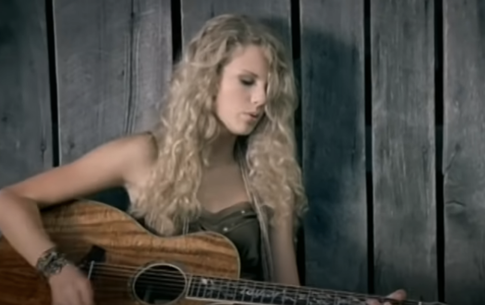 Woman with curly hair playing an acoustic guitar