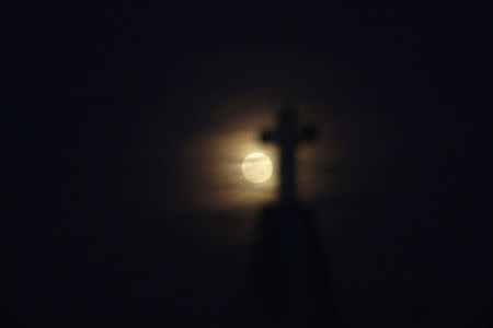 The full moon is seen ahead of a total lunar eclipse, known as the "super blood wolf moon", at a cemetery in Ciudad Juarez, Mexico January 20, 2019.REUTERS/Jose Luis Gonzalez