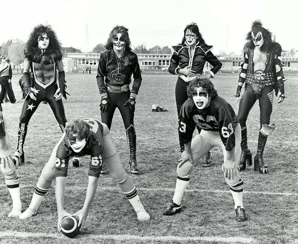 In this Oct. 9, 1975, file photo in Cadillac, Mich., members of the rock band Kiss, from top left — Paul Stanley, Peter Criss, Ace Frehley and Gene Simmons — line up behind two members of the Cadillac High School Vikings football team wearing Kiss facepaint.