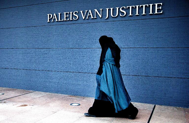A woman wearing a burqa walks past the Palace of Justice in The Hague