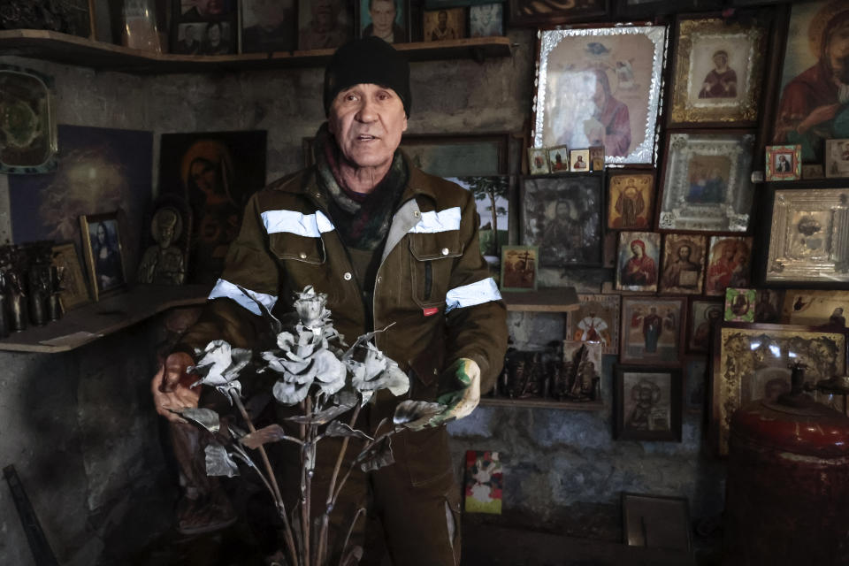 Viktor Mikhalev shows roses transformed from weapons and ammunition into flowers of war standing in a workshop in his house in Donetsk, Russian-controlled Donetsk region, eastern Ukraine, Saturday, March 4, 2023. Mikhalev, trained as a welder, lives and works in a house whose fence and door are decorated with forged flowers and grapes. (AP Photo/Alexei Alexandrov)