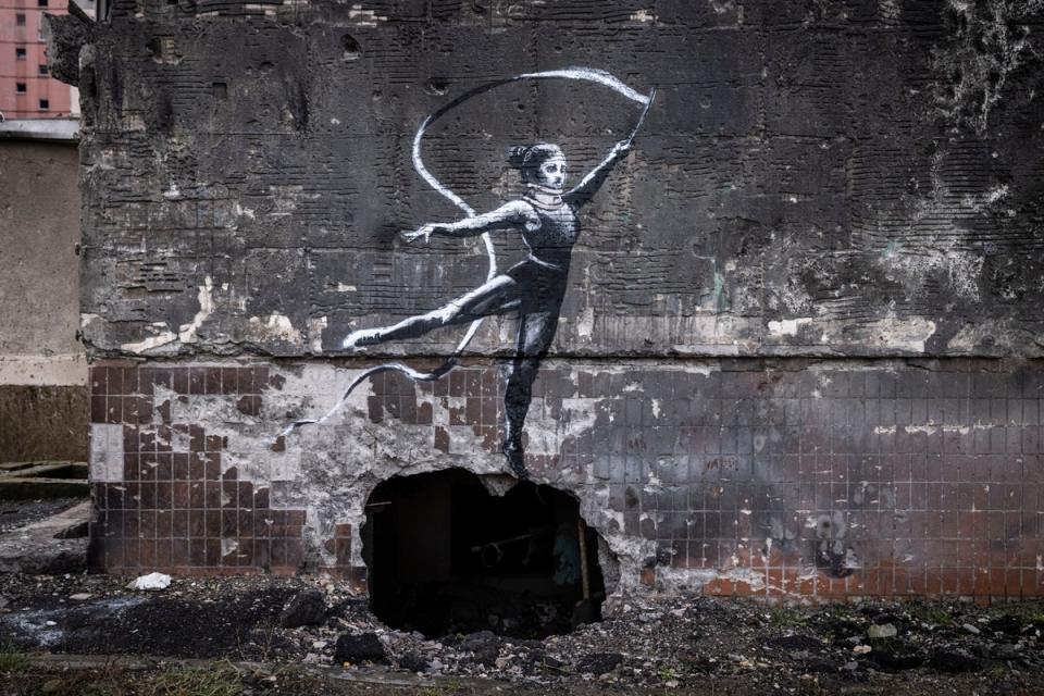 Graffiti of a woman in a leotard and a neck brace waving a ribbon is seen on the wall of a destroyed building in Irpin (Getty Images)