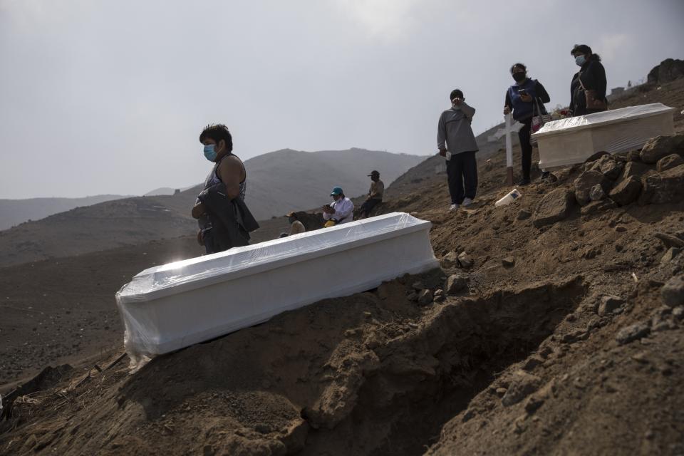 Familiares se reúnen para el entierro de un ser querido que se sospecha que murió por el nuevo coronavirus, en el cementerio de Nueva Esperanza, en las afueras de Lima, Perú, el miércoles 27 de mayo de 2020. (AP Foto/Rodrigo Abd)