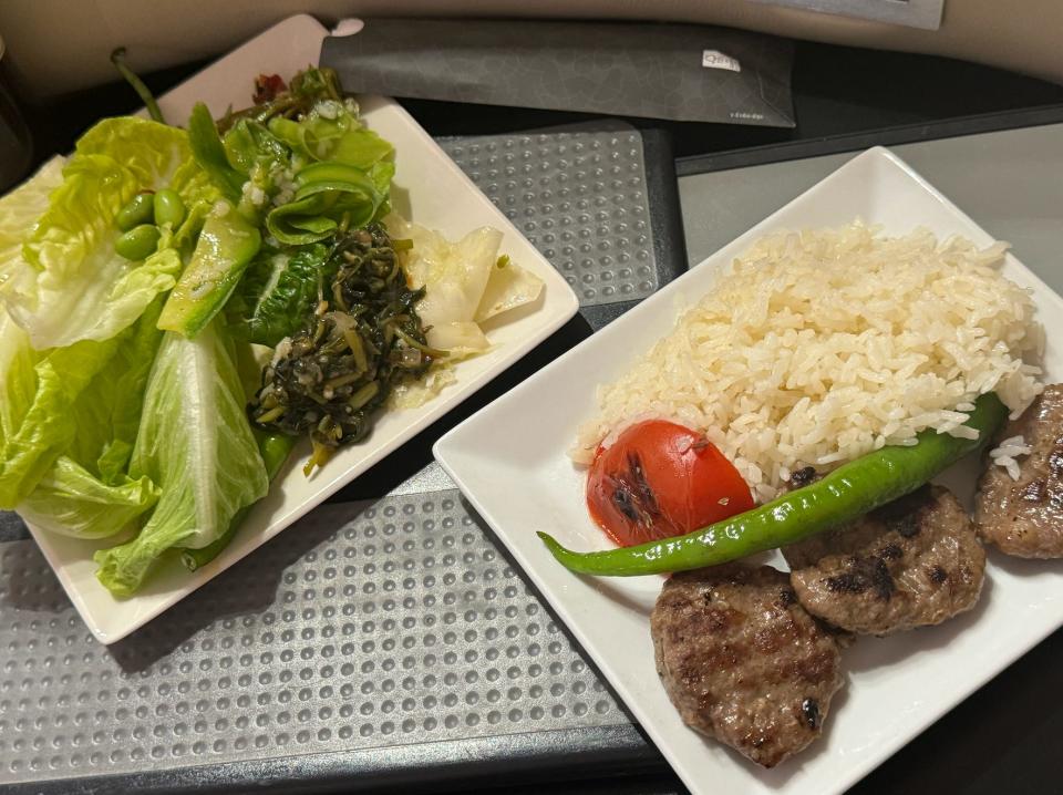 A plate of salad and a plate of kofta with rice.