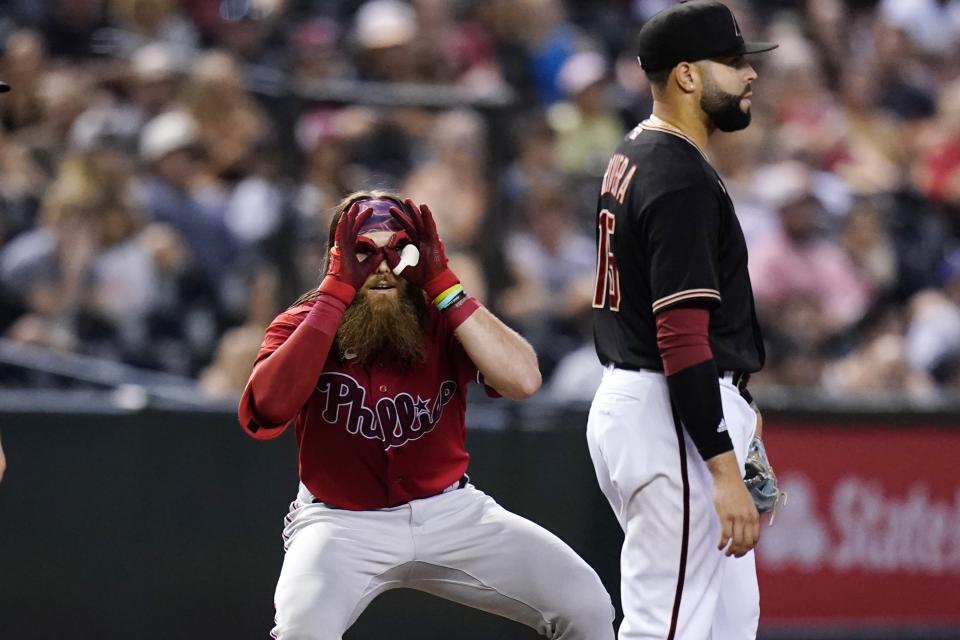 Philadelphia Phillies' Brandon Marsh, left, celebrates his two-run triple as he looks back at the dugout, while standing next to Arizona Diamondbacks third baseman Emmanuel Rivera during the fifth inning of a baseball game Wednesday, Aug. 31, 2022, in Phoenix. (AP Photo/Ross D. Franklin)