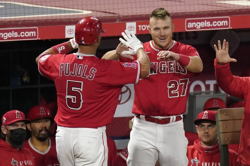 Los Angeles Angels' Albert Pujols, left, is congratulate by Mike Trout after hitting a solo home run during the seventh inning of a baseball game against the Texas Rangers Tuesday, April 20, 2021, in Anaheim, Calif. (AP Photo/Mark J. Terrill)