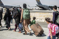 FILE - In this file photo, provided by the U.S. Marine Corps, families walk towards their flight during ongoing evacuations at Hamid Karzai International Airport, in Kabul, Afghanistan, on Aug. 24, 2021. A year after America's tumultuous and deadly withdrawal from Afghanistan, assessments of its impact are divided — and largely along partisan lines. (Sgt. Samuel Ruiz/U.S. Marine Corps via AP, File)