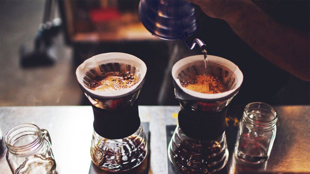 A person preparing two cups of drip coffee