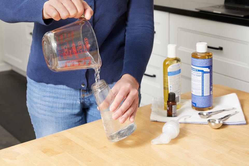 Woman making foaming hand soap adds water to the dispenser.