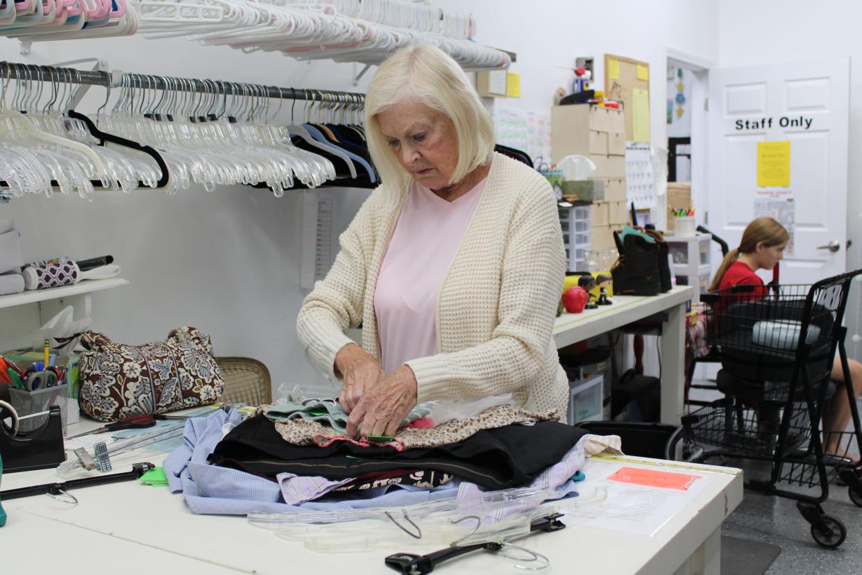 Dema Green adds pricing tags to clothing at the Bedford Lion’s Den Resale Shop.