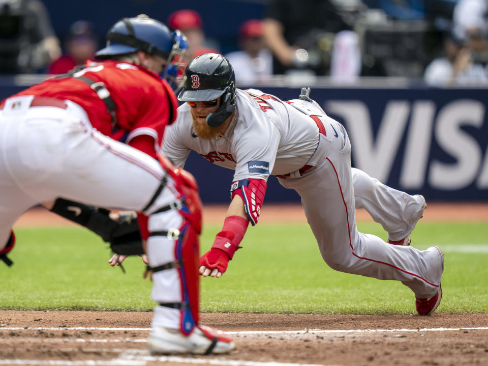 Boston Red Sox Justin Turner dives in to score past Toronto Blue Jays catcher Danny Jansen during the fifth inning of a baseball game in Toronto on Saturday, July 1, 2023. (Frank Gunn/The Canadian Press via AP)