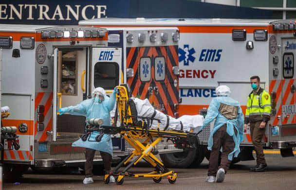 PHOTO: EMTs rush a patient to the emergency room at Massachusetts General Hospital in Boston, March 24, 2020, as the number of confirmed Massachusetts cases of coronavirus soars to near 5,000. (The Boston Globe via Getty Images)