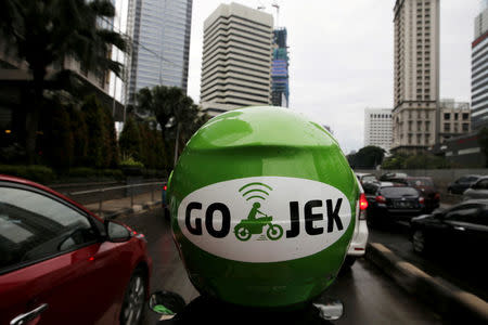 FILE PHOTO: A Gojek driver rides his motorcycle through a business district street in Jakarta, Indonesia, June 9, 2015. REUTERS/Beawiharta/File Photo