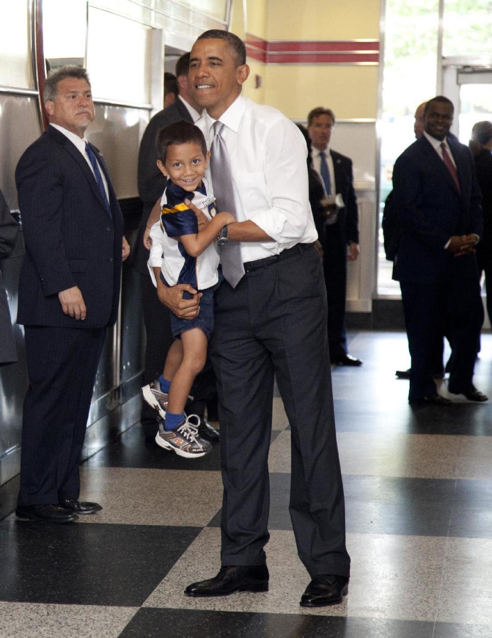 President Barack Obama picks up a boy as he visits The Varsity restaurant, Tuesday, June 26, 2012, in Atlanta. (AP Photo/Carolyn Kaster)