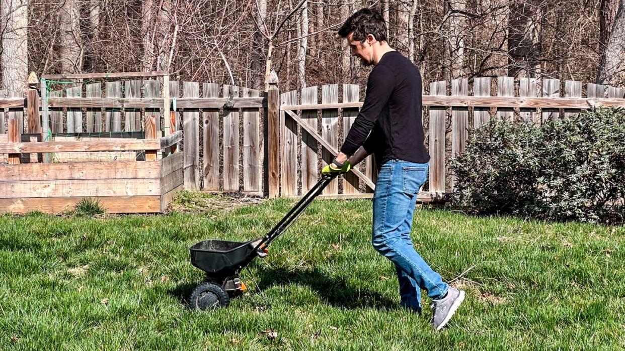 a person pushing a fertilizer spreader