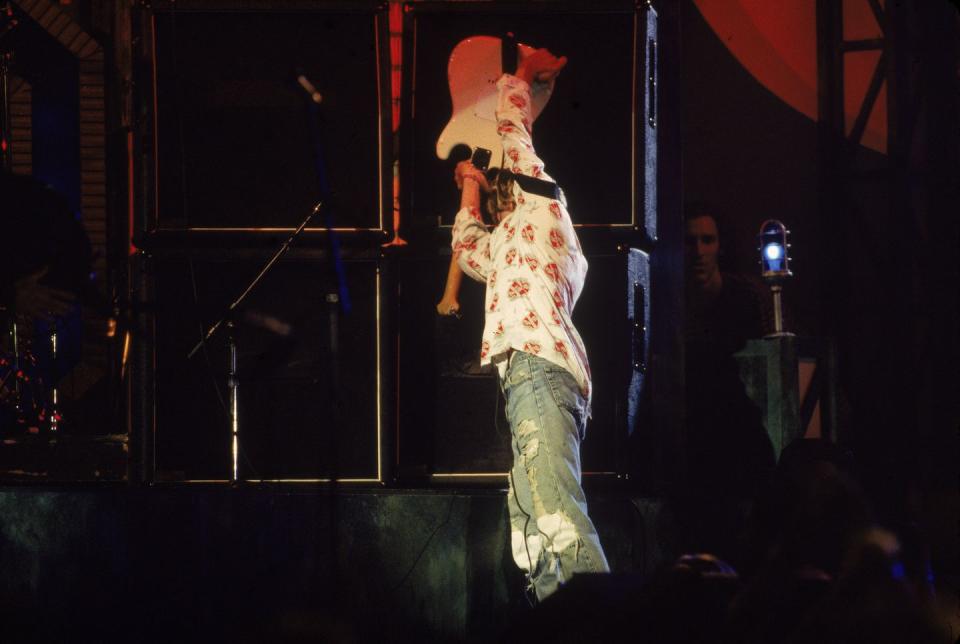 <p>Kurt Cobai, holding his guitar over his head in preparation to smash it after performing with Nirvana at the MTV VMAs in 1992. </p>