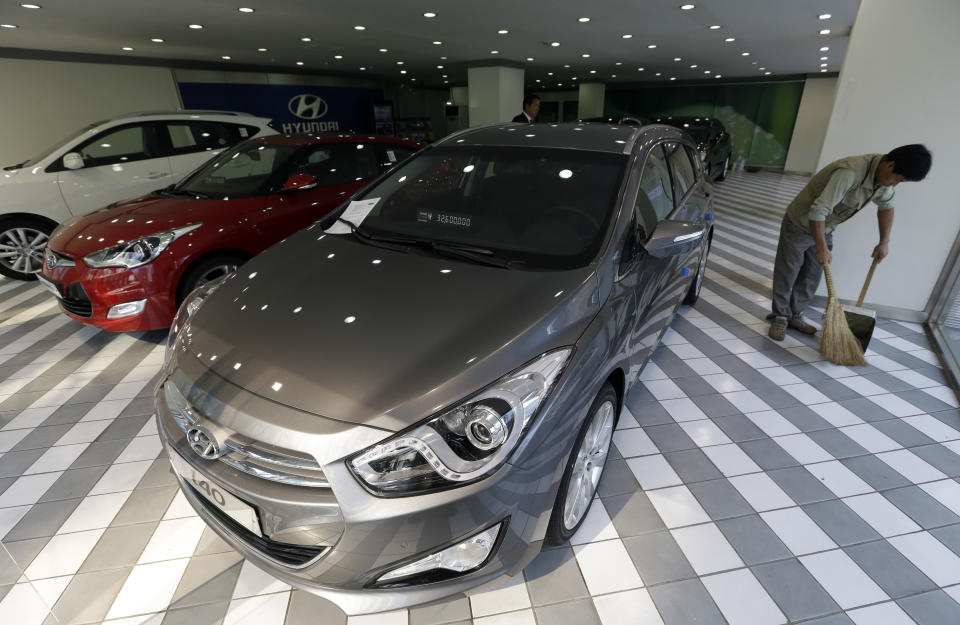 A man sweeps the floor of a Hyundai Motor's showroom in Seoul, South Korea, Thursday, Oct. 25, 2012. Hyundai Motor Co. suffered a fall in third quarter profit versus the previous quarter after strikes dented vehicle production. (AP Photo/Lee Jin-man)