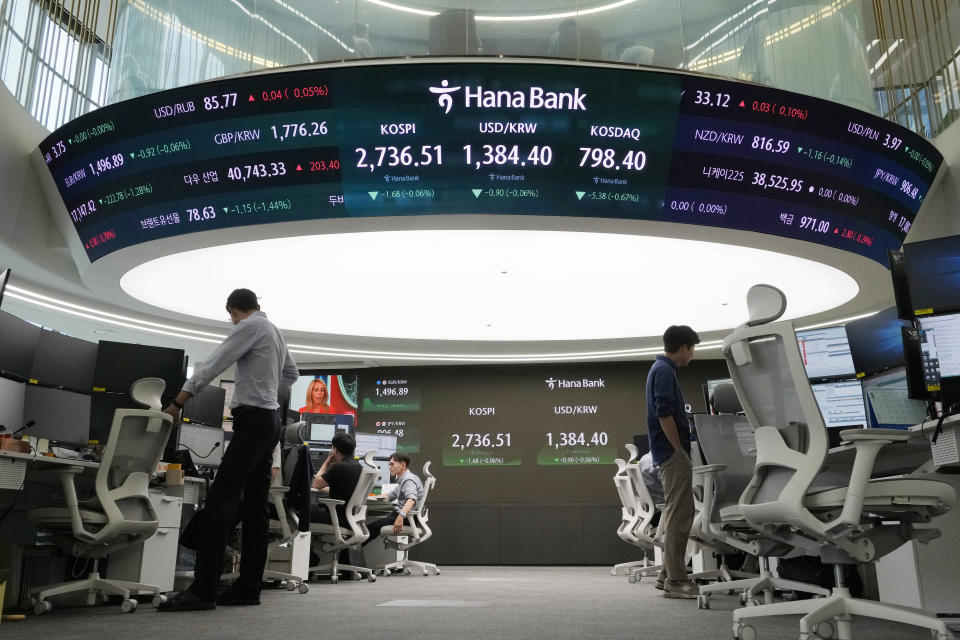 Currency traders work near the screen showing the Korea Composite Stock Price Index (KOSPI), top center left, and the foreign exchange rate between U.S. dollar and South Korean won, top center, at the foreign exchange dealing room of the KEB Hana Bank headquarters in Seoul, South Korea, Wednesday, July 31, 2024. (AP Photo/Ahn Young-joon)