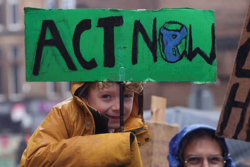 Un niño sostiene un cartel mientras la gente protesta durante la Conferencia de las Naciones Unidas sobre el Cambio Climático (COP26), en Glasgow, Escocia, Gran Bretaña, el 6 de noviembre de 2021.