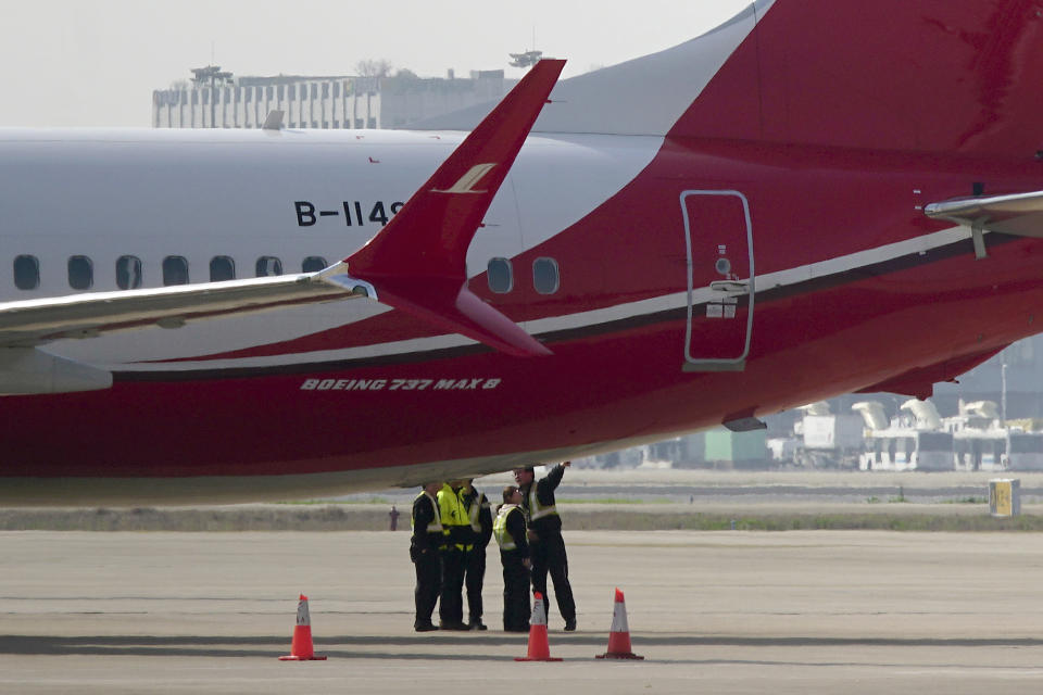 Ground crew chat near a Boeing 737 MAX 8 plane operated by Shanghai Airlines parked on tarmac at Hongqiao airport in Shanghai, China, Tuesday, March 12, 2019. U.S. aviation experts on Tuesday joined the investigation into the crash of an Ethiopian Airlines jetliner that killed 157 people, as a growing number of airlines grounded the new Boeing plane involved in the crash. (AP Photo)