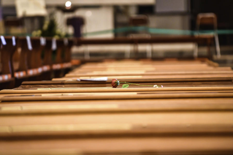 In this Thursday, March 26, 2020 photo, a red rose lies on a coffin lined up along others inside the San Giuseppe church in Seriate, one of the areas worst hit by coronavirus, near Bergamo, Italy, mark spaces where coffins are to be placed before being taken to a crematory. Italy is seeing a slight stabilizing in its confirmed coronavirus infections two weeks into the world’s most extreme nationwide shutdown, but the virus is taking its silent spread south after having ravaged the health care system in the north. The new coronavirus causes mild or moderate symptoms for most people, but for some, especially older adults and people with existing health problems, it can cause more severe illness or death. (Claudio Furlan/LaPresse via AP)