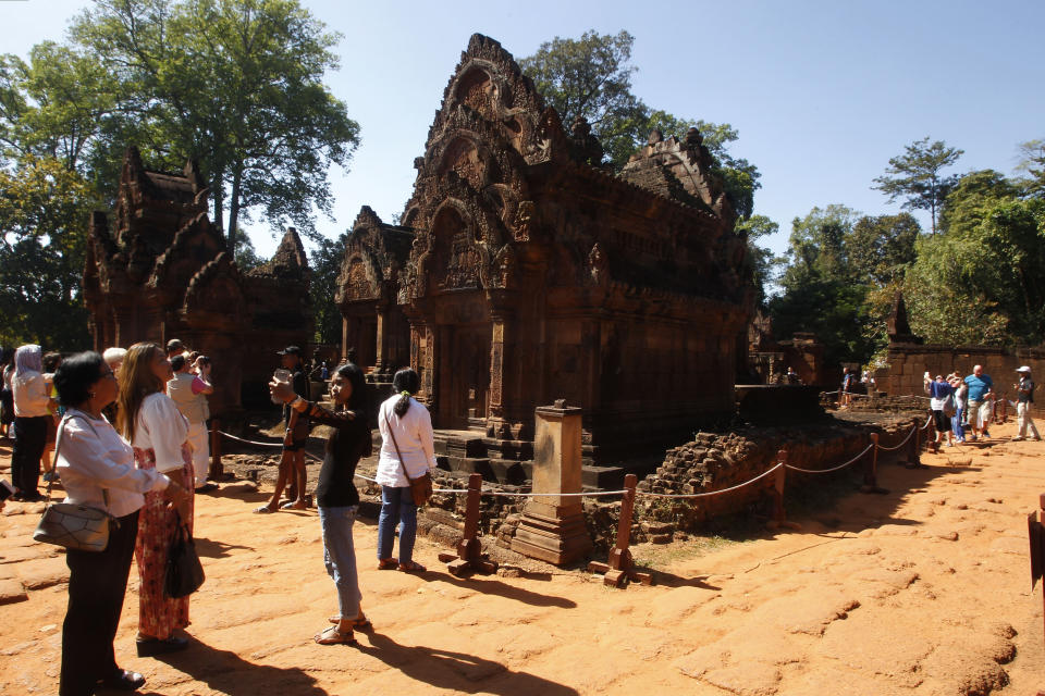 FILE - In this Dec. 23, 2017, file photo, tourists visit Banteay Srey temple outside Siem Reap, Cambodia. Cambodia is closing the Angkor temple complex to visitors because of a growing COVID-19 outbreak. On Thursday, April 8, 2021, the Health Ministry said 113 cases were reported from local transmission, with two deaths. The ministry traced the outbreak to a foreign resident who broke hotel quarantine to visit a nightclub. (AP Photo/Heng Sinith, File)