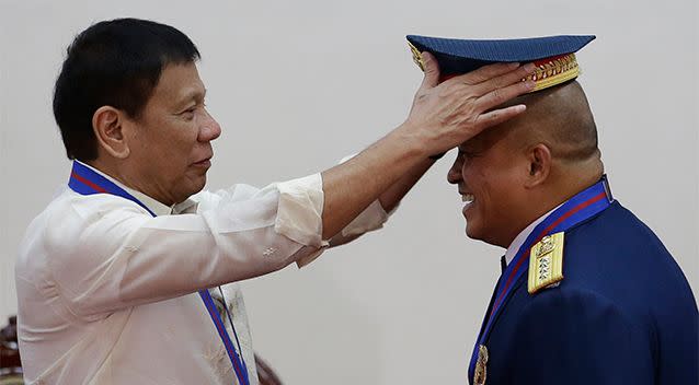 Philippine President Rodrigo Duterte, left, places the hat of the new Police Chief, Director General Ronald Dela Rosa, during the 