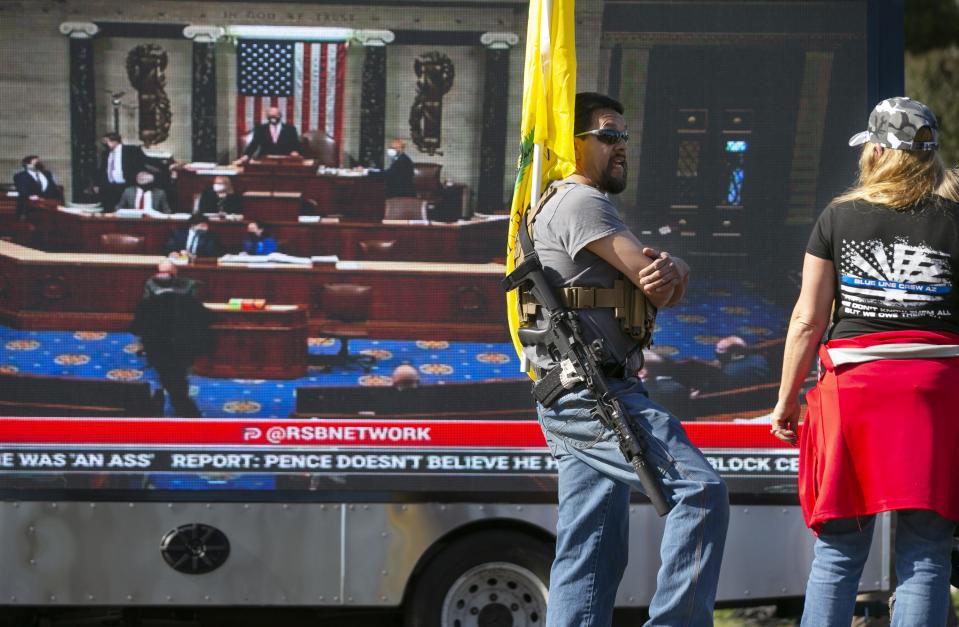 An armed man stands guard outside the state Capitol in Phoenix during a pro-Trump rally as the U.S. Congress meets in Washington, D.C., to certify the results of the presidential election on Jan. 6, 2021.