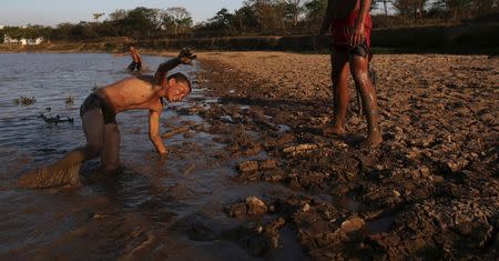 Natalino Pereira (L), 12, and Orlando Fernandez, 15, joke next to the cracked ground of the Itaim dam as the eight-month rationing of water continues as a result of a record drought, in Itu, October 28, 2014. REUTERS/Nacho Doce