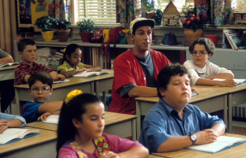 Adam Sandler sitting at a desk in a class for children in a scene from the film 