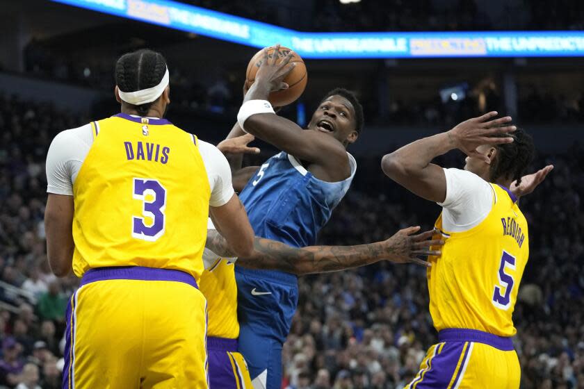 Minnesota Timberwolves guard Anthony Edwards, center, works toward the basket as Los Angeles Lakers forwards Anthony Davis (3) and Cam Reddish (5) defend during the first half of an NBA basketball game, Thursday, Dec. 21, 2023, in Minneapolis. (AP Photo/Abbie Parr)