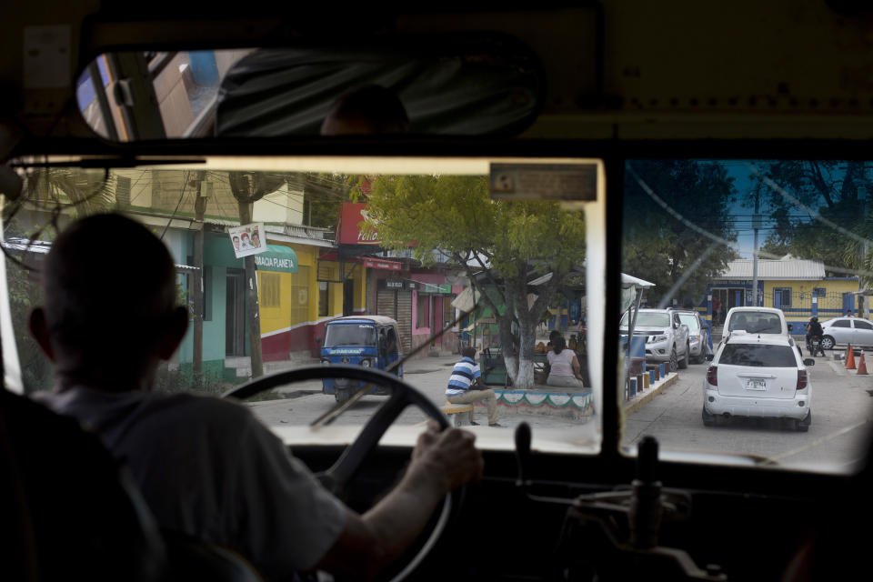 In this Oct. 31, 2018 photo, a driver steers a bus transporting relatives of Wilmer Gerardo Nunez to a small cemetery for Nunez's burial ceremony, in San Pedro Sula, Honduras. Nunez was one of 72 migrants killed by members of the Zeta drug cartel in 2010 on a ranch in San Fernando, across the border from Texas. (AP Photo/Moises Castillo)