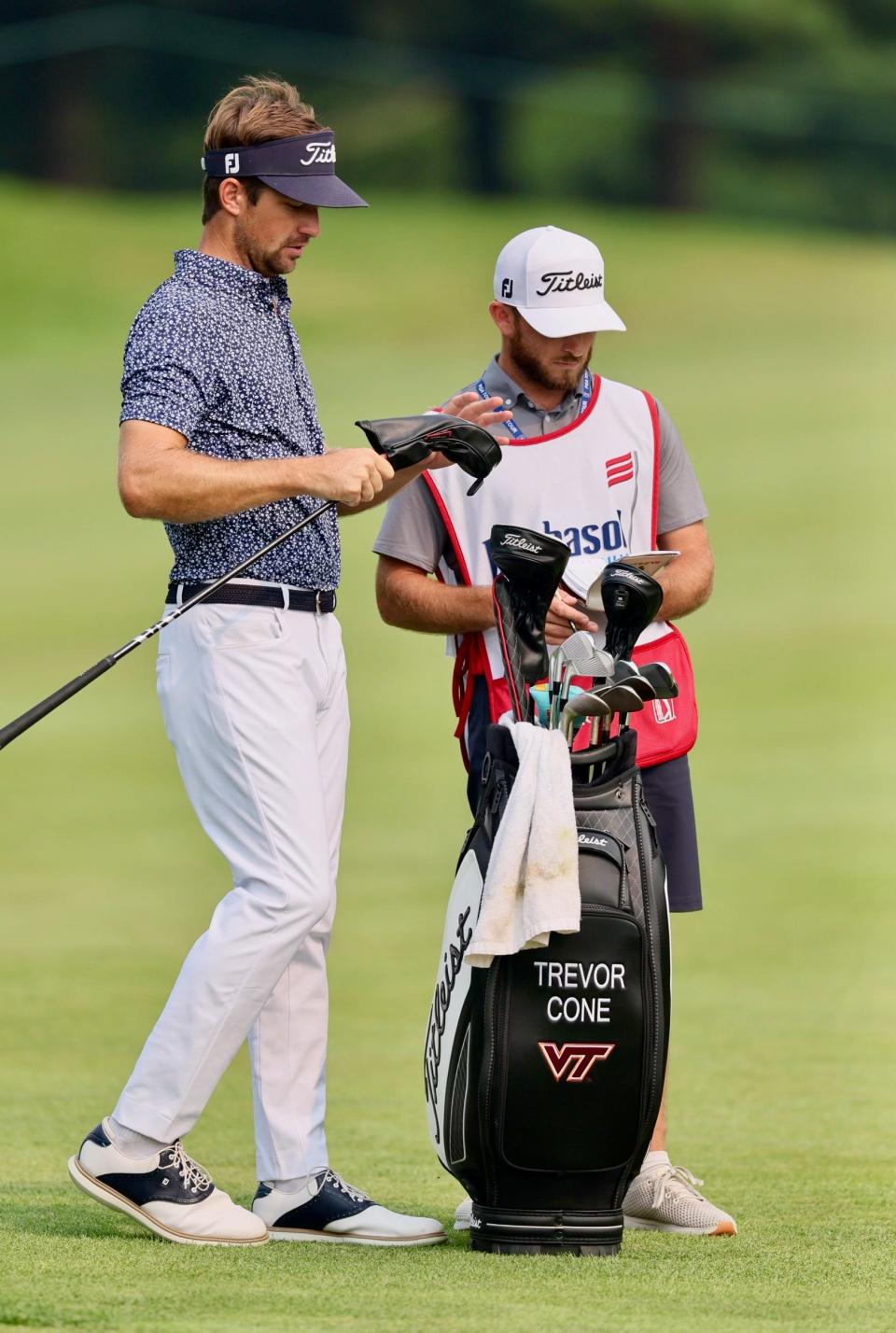 Former St. John's golfer Dan Woodbury, right, helps his former college teammate Trevor Cone, left, prepare for Cone’s second shot on the 11th hole last Sunday in the Barbasol Championship.